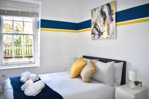 a bedroom with a white bed with yellow and blue stripes at Lux 2-Bed, Central, Balcony, Free Secure Parking in Reading
