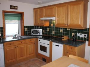 a kitchen with wooden cabinets and a microwave at 3 Bed in Isle of Barra CA295 in Ersary