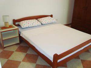 a bed with two pillows and a night stand at Apartments Rolovina in Tivat
