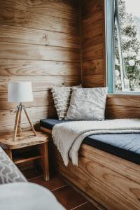 a bedroom with wooden walls and a bed with a window at Tatahi Lodge Beach Resort in Hahei