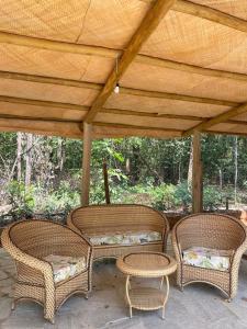 three wicker chairs and tables under a wooden roof at Sítio Quinta da Mata Chalé Amarelo in Pirenópolis