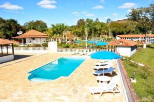 a swimming pool with chairs and umbrellas at Pousada temática Estrada Real in Caxambu