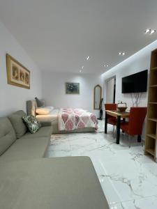 ein Wohnzimmer mit einem Sofa, einem Bett und einem Tisch in der Unterkunft Midnight Apartments in Tirana