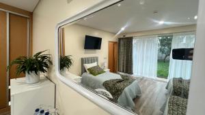 a mirror reflecting a bedroom with a bed and a window at A Fonte in Estarreja