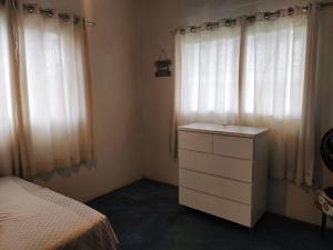 a bedroom with a bed and a dresser and windows at Casa confortável, pertinho da cidade e conectada a natureza in Brasília