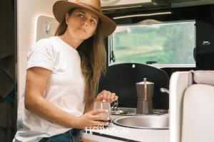 une femme dans un chapeau tenant un verre de vin dans l'établissement Live On The Horizon 1, à Ribadesella