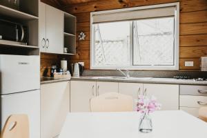 a kitchen with white cabinets and a window at Tatahi Lodge Beach Resort in Hahei