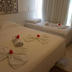 two beds with white towels and red flowers on them at Nannai Residence, Beira-mar - Porto de Galinhas / Muro Alto (BDJ06) in Porto De Galinhas