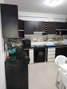 eine Küche mit schwarzen Schränken und schwarzen Arbeitsplatten in der Unterkunft Gardella House, Casa - Hotel in Ica