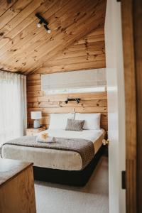 - une chambre avec un lit et un plafond en bois dans l'établissement Tatahi Lodge Beach Resort, à Hahei