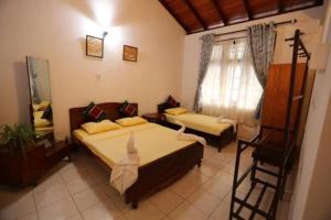 a room with two beds and a chair in it at Reverie Hill Bungalow, Kandy in Kandy