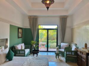 a bedroom with a bed and chairs and a large window at La Villa Des Golfs & PinkCactus in Marrakesh