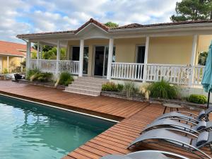 ein Haus mit einer Holzterrasse und einem Pool in der Unterkunft Villa du Golf Eden Parc in Lacanau-Océan