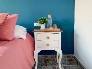 a bed with a white nightstand with a bottle on it at Habitaciones privadas cerca de la playa y aeropuerto en casa compartida con otros huéspedes in Playa Honda