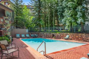 a swimming pool with chairs and a brick wall at The Galatyn Lodge in Vail