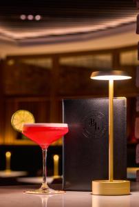 una bevanda rossa in un bicchiere di Martini accanto a una lampada di The James Hotel a Tralee