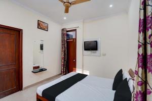 a bedroom with a bed and a tv on the wall at Super OYO OM SAI RAM GUEST HOUSE in Gurgaon