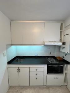 a small kitchen with white cabinets and a sink at Dpto Olleros in Buenos Aires