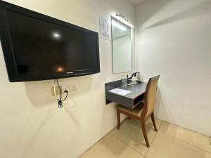 telewizor z płaskim ekranem wiszący na ścianie z krzesłem w obiekcie Alia Express Hotel Twelve a12 Kuantan w mieście Kuantan