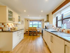 cocina con armarios blancos y suelo de madera en 3 bed in Builth Wells 78329 en Crickadarn