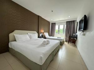 a hotel room with two beds and a television at Alia Express Hotel Twelve a12 Kuantan in Kuantan