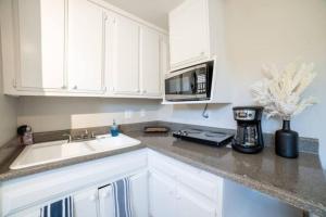 a white kitchen with a sink and a microwave at Netflix, Bikes, Stocked Kitchenette, Beach Gear in Ventura