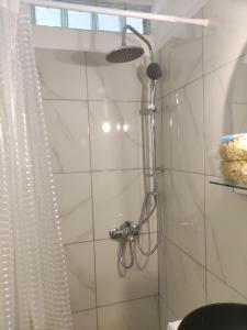 een douche met een douchekop in de badkamer bij Όμορφο διαμέρισμα με μπαλκόνι στη Σαρωνίδα in Saronida