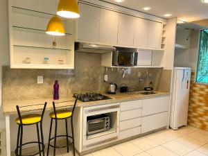 uma cozinha com armários brancos e bancos de bar amarelos em Coliving Stela Mares em Florianópolis