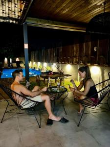 a man and a woman sitting in chairs by a pool at BROTHERS HOSTEL in Villa Allende