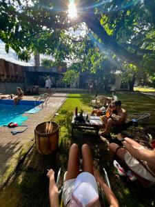 un grupo de personas yaciendo en la hierba junto a una piscina en BROTHERS HOSTEL en Villa Allende