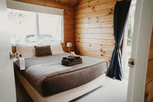 a bedroom with a bed in a wooden cabin at Tatahi Cove Back Packer in Hahei