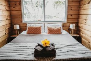 Un dormitorio con una cama con una flor amarilla. en Tatahi Cove Back Packer en Hahei