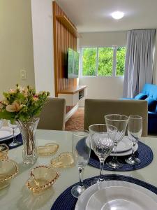 a table with glasses and plates and a vase with flowers at Apartamento Lótus Ar Cond Pertinho FIG e Centro in Garanhuns