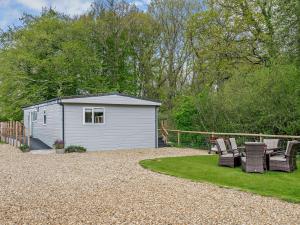 a small white shed with chairs in a yard at 2 Bed in Woodgreen 82875 in Godshill