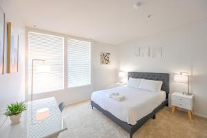 a white bedroom with a bed and a table and windows at Cozy Home Management in MDR in Los Angeles