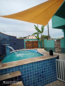 una piscina con una pared de azulejos azules y una sombrilla en Casa com piscina , churrasqueira, Wi-Fi, em rua de Areia à 1km da praia, bairro sussegado, proíbido uso de som extremamente alto ideal para descansar, en Itanhaém