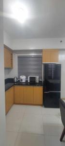a kitchen with a black refrigerator and brown cabinets at 1608 Three Bedrooms With 1 free parking, swimming pool WiFi and Netflix at Northpoint Camella Condominium Bajada Davao City in Davao City