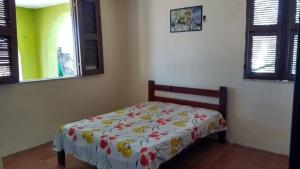 een slaapkamer met een bed met een bloemenbed bij Casa Temporada Prainha - Aquiraz in Aquiraz