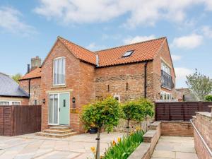 a brick house with a white door and a fence at 2 Bed in Thirsk 48116 in Carthorpe