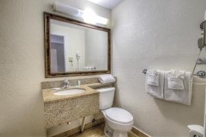 a bathroom with a toilet and a sink and a mirror at La Bella Oceanfront Inn - Daytona in Daytona Beach