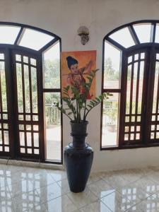 a black vase with flowers in a room with windows at Moon Deck Villa in Katunayaka