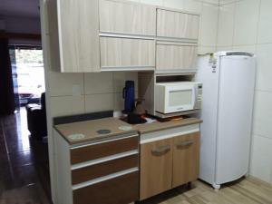 una pequeña cocina con nevera y microondas en Casa no Campeche para veraneio com internet en Florianópolis