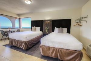 two beds in a hotel room with a view of the ocean at La Bella Oceanfront Inn - Daytona in Daytona Beach