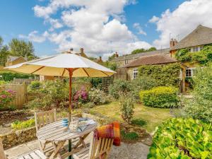 a wooden table with an umbrella in a garden at 3 Bed in Beaminster 50738 in Stoke Abbott