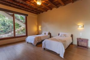 two beds in a room with a large window at El Jardin Lodge & Spa in Puerto Misahuallí