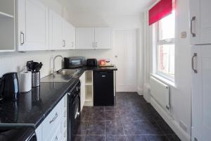 a kitchen with white cabinets and a black counter top at Rochester Slopes - Free Street Parking in Strood