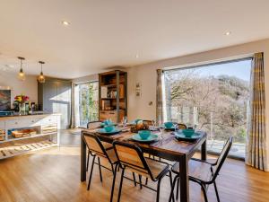 une salle à manger avec une table, des chaises et une grande fenêtre dans l'établissement 3 Bed in Dolgellau 90805, à Llanelltyd