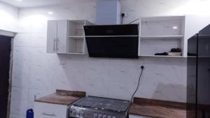 uma cozinha com um fogão e armários brancos em Motalvin Court em Lagos