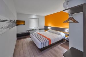 a bedroom with a bed with an orange wall at City Express Junior by Marriott San Luis Potosi Carranza in San Luis Potosí