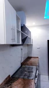 uma cozinha com um fogão e armários brancos em Motalvin Court em Lagos